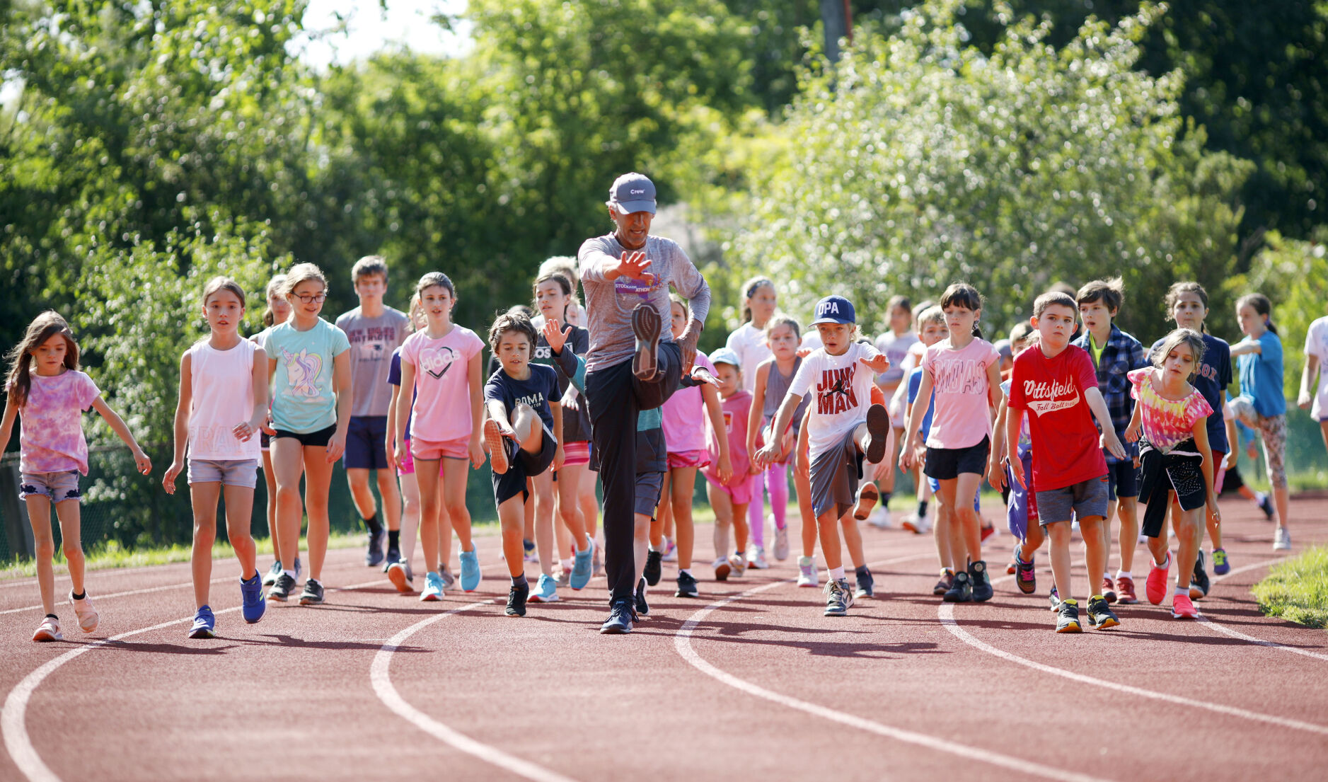 Kent Lemme leads kids in toe touches on running track